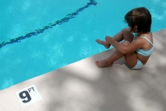 Child sitting on side of swimming pool